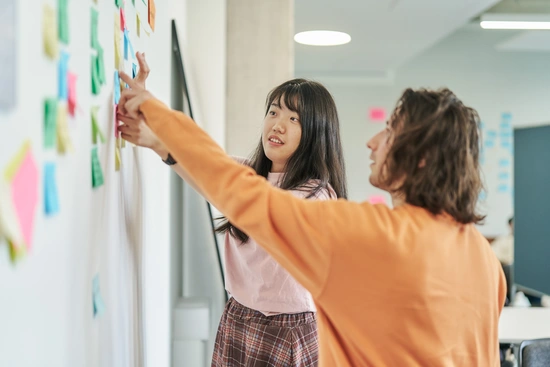 Beratung-Promotion-THI-Schroll Zwei Personen stehen vor einem Flipchart und besprechen die verschiedenen Promotionsmöglichkeiten, die es an der Doctoral School der Technischen Hochschule Ingolstadt gibt: Promotionszentrum KI & Informatik, Promotionszentrum Ingenieurwissenschaften sowie kooperative Promotion und Verbundpromotion mit BayWISS, dem Bayerischen Wissenschaftsforum.