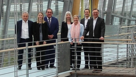 A group of seven people in a modern glass stairwell