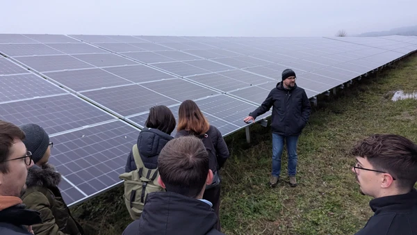 Gruppe Studierender vor einer großen PV Anlage auf dem Feld