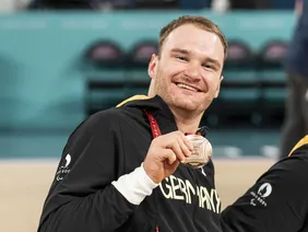 So sehen Sieger aus: Lukas Gloßner mit seiner Medaille (Foto: Ana Sasse). Portrait von Student Lukas Glossner bei einem sportlichen Wettbewerb, wie er seine Medaille zeigt