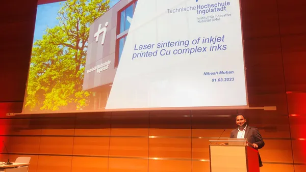 Nihesh Mohan is doing his doctorate in Professor Gordon Elger's research group on the topic of ‘Particle-free copper inks for additive electronics’ (Photo: THI). Bild von Präsentation zum AGE-Projekt auf der Leinwand und Sprecher